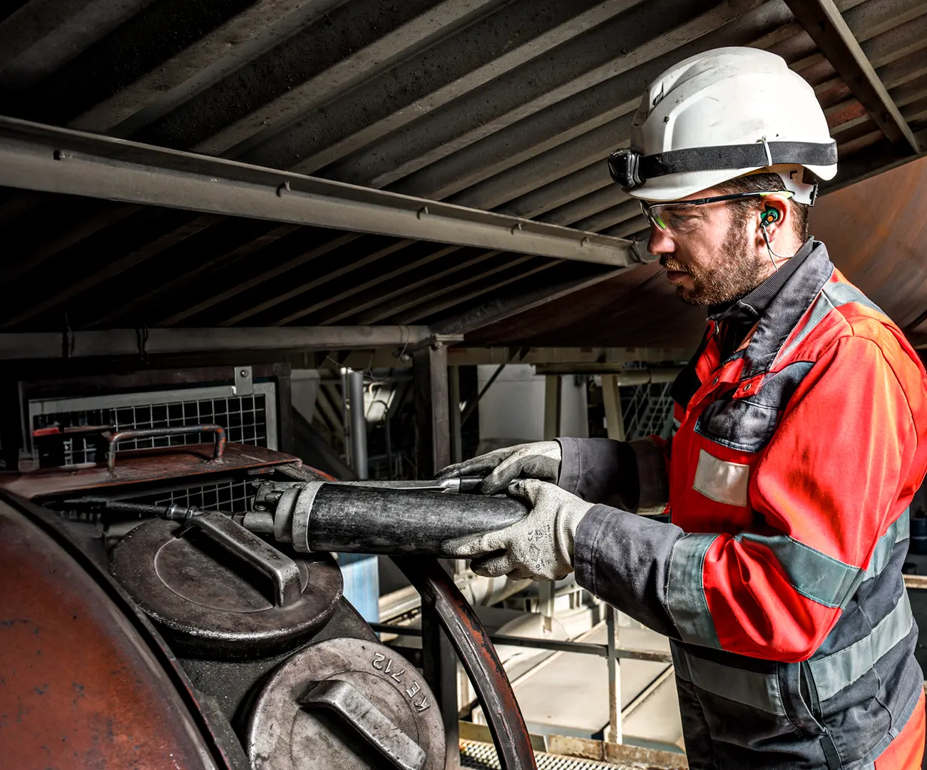 Industriemitarbeiter mit Helm, Gehörschutz und Sicherheitskleidung bei der Arbeit – ausgestattet mit Otoplastiken zum individuellen Gehörschutz in lauter Umgebung.