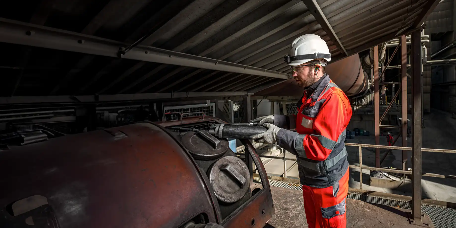 Industriemitarbeiter mit Helm, Gehörschutz und Sicherheitskleidung bei der Arbeit – ausgestattet mit Otoplastiken zum individuellen Gehörschutz in lauter Umgebung.